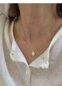 Detailed close-up of 925 silver opal necklace on neck with white knit sweater