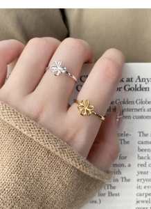 Close-up of minimalist hollow flower rings in silver and gold on a model finger