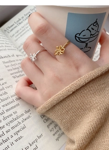 Detailed view of gold and silver hollow flower rings worn on hand in a cozy aesthetic setting