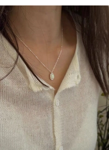Close-up of elegant 925 silver necklace with white oval opal pendant worn by a model
