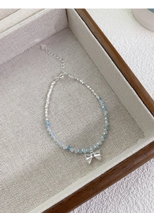 Detailed macro of S925 silver bow bracelet with aquamarine beads on a display tray