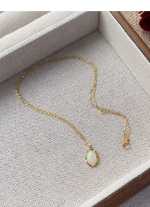 Detailed view of an oval opal pendant necklace on a wooden jewelry display tray