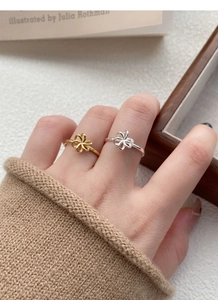 Close-up of S925 sterling silver hollow flower rings worn on hand in a cozy setting