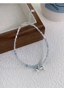 Detail of S925 silver bracelet with blue crystal beads and a delicate bow charm