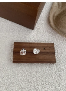 Detailed view of polished S925 sterling silver twisted teardrop earrings on a wood display