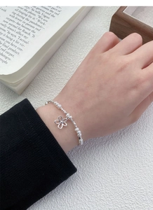 Detailansicht von 925 Silber Blumenanhänger und Süßwasserperlenarmband am Handgelenk