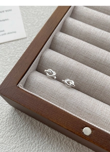 Detailed view of S925 sterling silver knotted stud earrings on a linen jewelry display