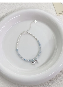 Detailed macro view of S925 sterling silver bow charm and blue faceted beads on a bracelet