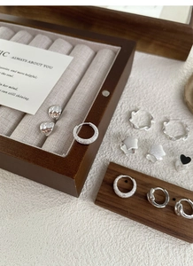 Detailed close-up of S925 sterling silver earrings set on a wooden jewelry display