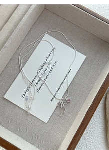 Dettaglio macro della collana a fiocco in argento S925 con gemma a cuore rosa e chiusura