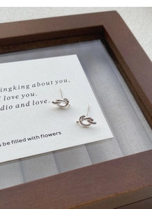 Close-up of minimalist S925 sterling silver knotted stud earrings on a card