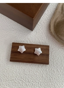 Detail view of matte silver star studs with brushed texture on wooden display stand