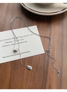 Detail of S925 sterling silver chain with Lucky plaque and polished bean pendant charm