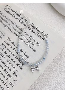 Detailed macro view of S925 silver bracelet featuring blue beads and a silver bow charm