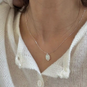 Elegant 925 sterling silver necklace with oval white opal pendant on a female model