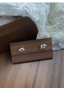 Detailed view of S925 sterling silver knotted stud earrings on a vintage wooden display