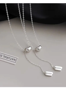 Close-up of S925 silver necklace with polished bean pendant and LUCKY engraved metal tag