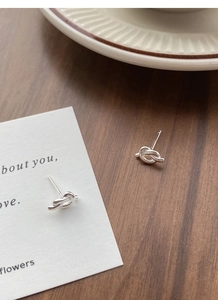 Macro shot of S925 sterling silver knot stud earrings on a rustic wooden table background