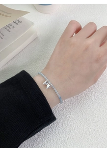 Detail of S925 silver bow charm bracelet with light blue beads on a female wrist