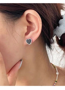 Detailed view of silver heart earrings with black enamel inlay on female model