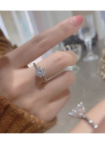 Close-up of a six-prong silver moissanite ring with a brilliant round cut on a finger