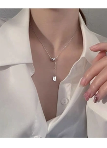 Detail of S925 sterling silver Y-shaped necklace with a lucky tag on a white shirt