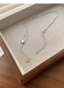 Detail of S925 sterling silver Lucky square tag and bean pendant necklace on jewelry box