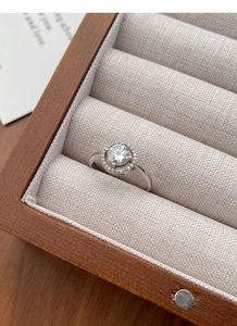 Dettaglio ravvicinato di un anello moissanite halo in una scatola regalo in legno pregiato