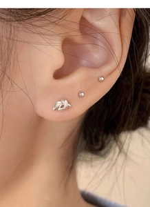 Macro shot of silver knot stud earrings and mini spheres set on a model ear