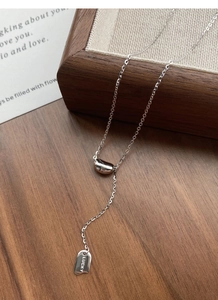 Detail of S925 silver lucky necklace with square pendant and polished bean drop on wood