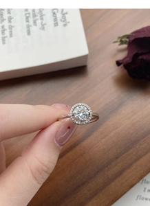 Dettaglio dell'anello in moissanite con incastonatura halo sulla mano elegante