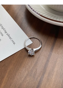 Macro shot of 1 carat moissanite ring with six-prong setting on a wooden table