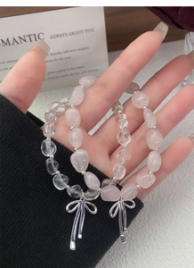 Nahaufnahme von rosafarbenen und weißen Kristallarmbändern mit Silber-Schleife