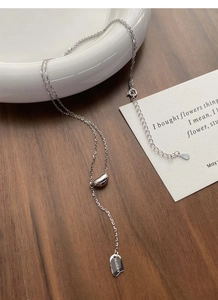 Macro shot of S925 sterling silver bean necklace with lucky engraved plate on wood background