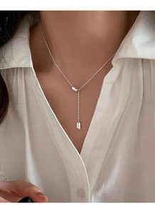 Detail of S925 sterling silver Y-shaped tassel necklace on a white shirt neckline