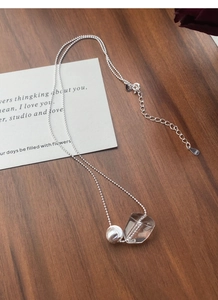 Close-up of S925 silver beaded chain with irregular crystal pendant on wood background