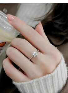 Close-up of a silver moissanite ring with six-prong setting on a woman's finger