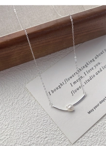 Detail of S925 silver necklace with white pearl on wooden tray and white card