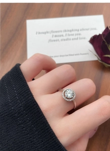 Primo piano dell'anello di fidanzamento halo moissanite indossato con stile regalo