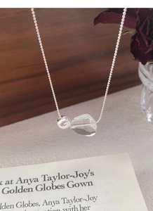 Detail of silver beaded chain with transparent crystal pendant over vintage roses