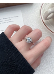 Dettaglio dell'anello di fidanzamento halo in moissanite e argento s925 sulla mano
