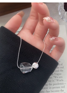 Detail shot of irregular crystal pendant and cat eye bead on silver beaded necklace