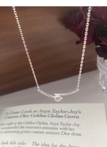 Detail of S925 silver pearl necklace displayed on vintage books with rose accents