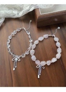 Detailansicht des S925 Silber-Schleifenanhängers an klaren und rosa Kristall-Armbändern