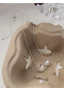 Macro detail of irregular transparent crystal and S925 sterling silver bead on a fine chain