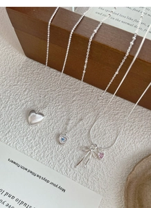 Dettaglio di collane in argento S925 con ciondoli a cuore e fiocco in diversi stili