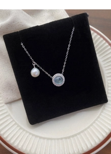 Detail of S925 silver necklace featuring round freshwater pearl and blue gemstone pendant