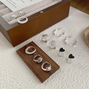 Elegant S925 sterling silver earring set with heart and star motifs on a wooden display