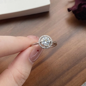 Anello halo classico in moissanite e argento 925 tenuto su uno sfondo di legno caldo