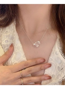 Detail of S925 silver necklace with irregular clear crystal pendant and white pearl on model